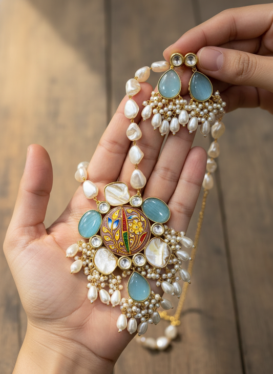 Ornate necklace with blue stones and pearl-like beads held in a hand against a blurred background